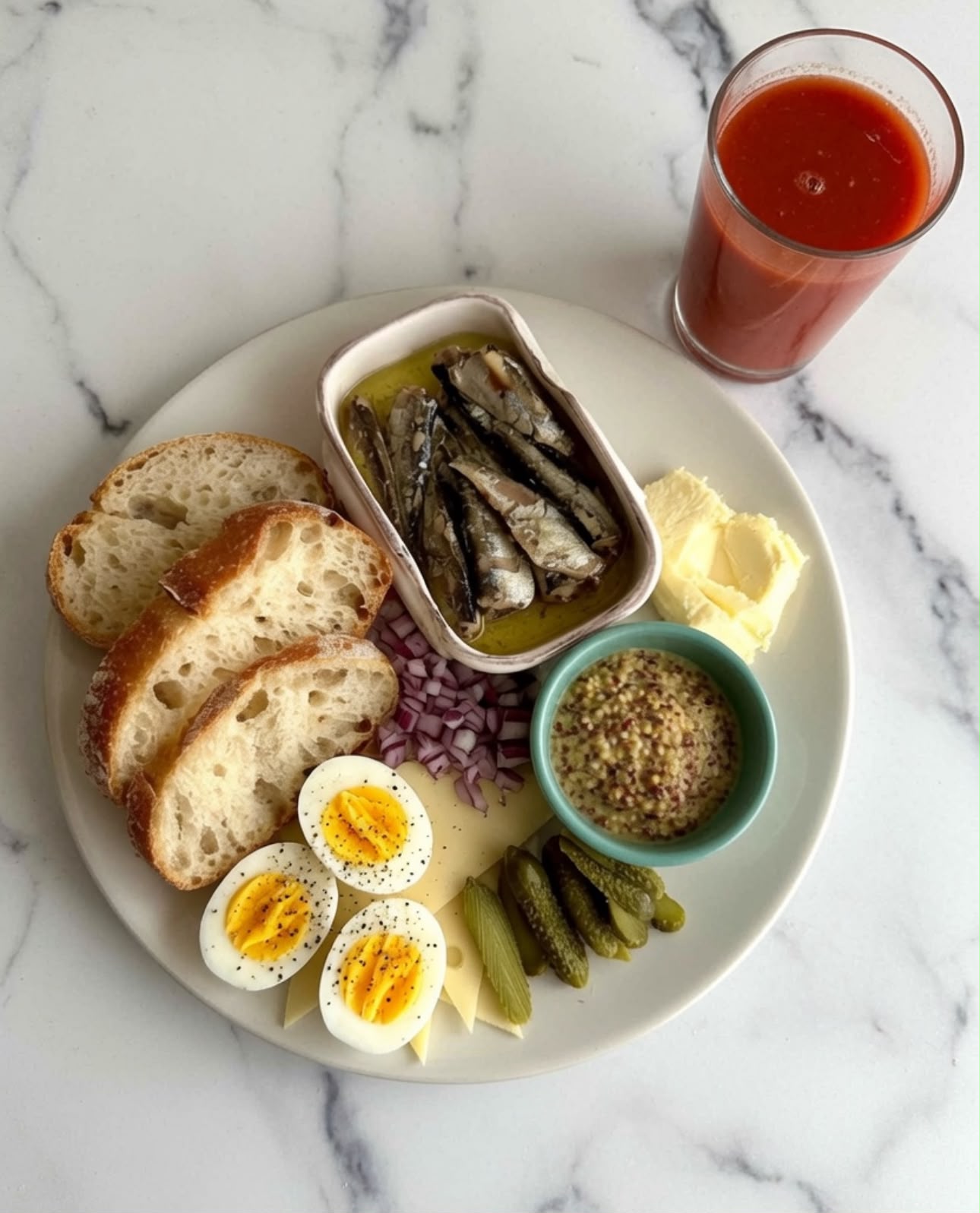 A plate of tinned sardines in olive oil with sourdough toast, hard-boiled eggs, whole-grain mustard, pickles, red onion, and a glass of tomato juice